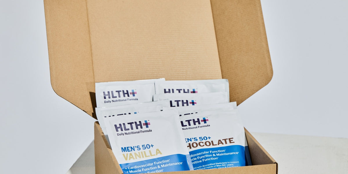 HLTH+ Men's 50+ Daily Nutritional Formula sachets in an open kraft box on a grey studio background — HLTH+