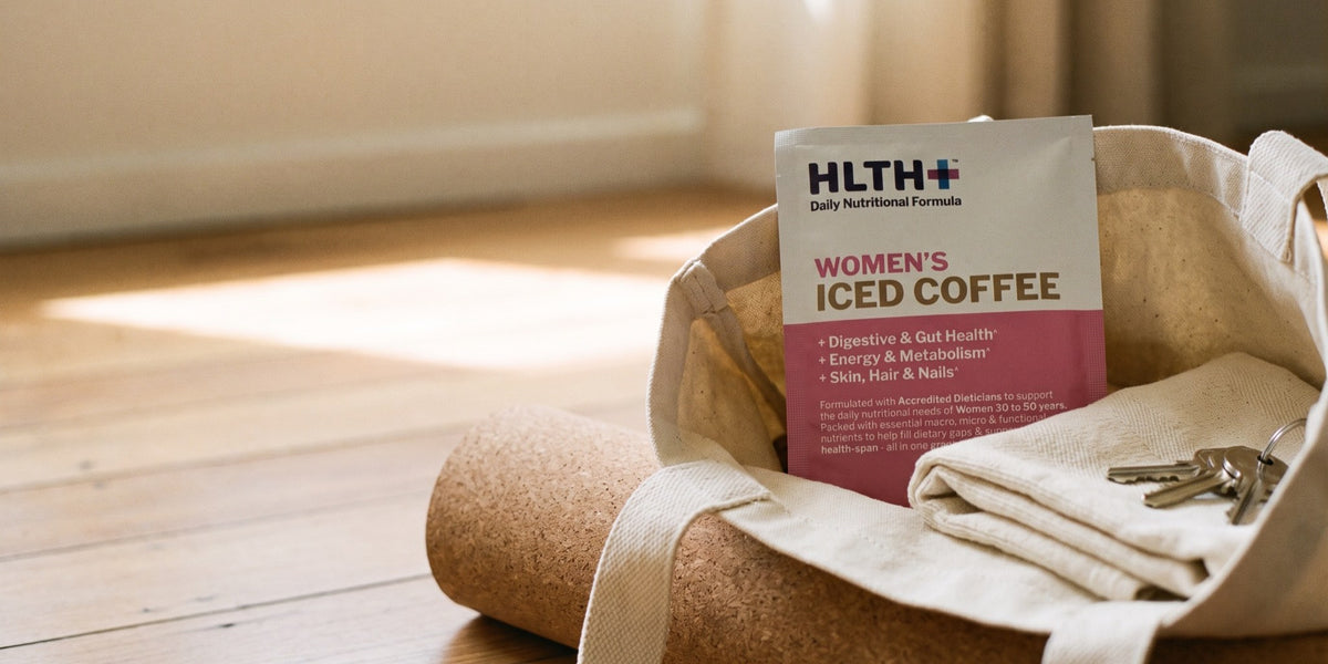 HLTH+ Women's Daily Nutritional Formula Iced Coffee sachet on cream linen in bright daylight — HLTH+