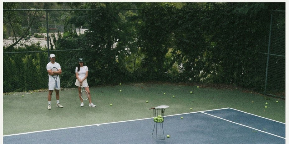 Three people on an outdoor tennis court on a sunny day, a man in a white cap playing a forehand in the foreground — HLTH+