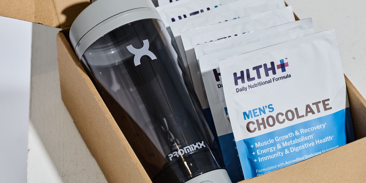 HLTH+ Men's Daily Nutritional Formula Chocolate sachets and a black electric shaker in an unboxing flat lay — HLTH+