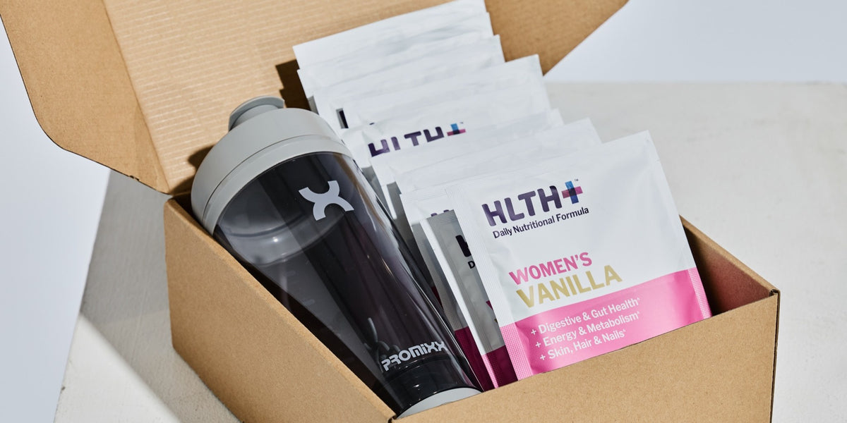 HLTH+ Women's Daily Nutritional Formula Vanilla sachets unboxed beside a charcoal electric shaker — HLTH+