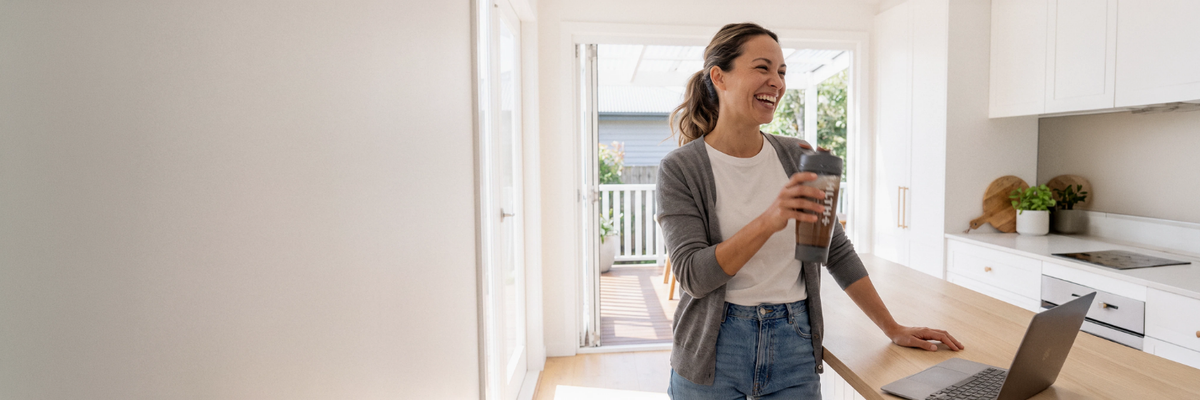 A woman with a HLTH+ shaker in her kitchen